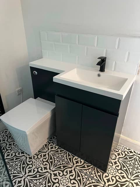 Fitted bathroom with dark vanity unit and metro tiles