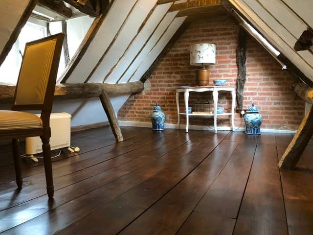 Converted loft room with exposed beams and dark wood floor